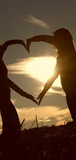 Silhouette of figures forming a heart at sunset.