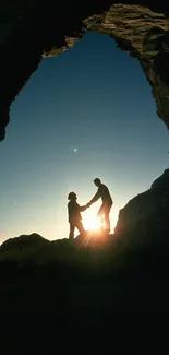 Silhouette of two figures in a cave during sunset.