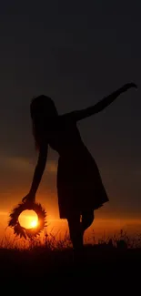 Silhouette with wreath at sunset against an orange and dark blue sky.