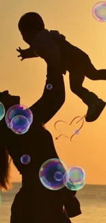 Mother lifting child silhouette with bubbles at sunset.