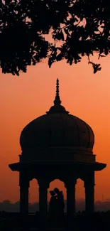 Silhouette of a pavilion against an orange sunset backdrop with romantic ambiance.