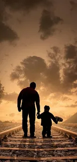 Silhouette of parent and child at sunset on railway tracks.