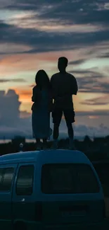 Silhouette of two people on a van at sunset.