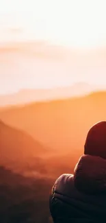 Serene view of sunset over mountains with a hiker watching.