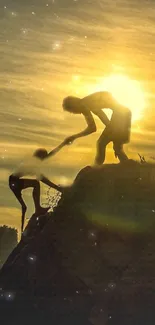 Silhouette of two people helping on a rocky hill at sunset.