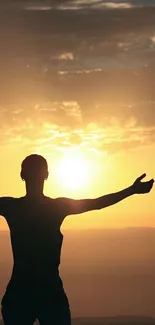 Silhouette of person with outstretched arms against a sunset sky.