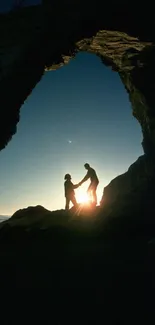 Silhouette of a couple under a rock arch at sunset with dramatic lighting.