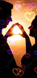 Silhouette of couple forming heart at sunset.