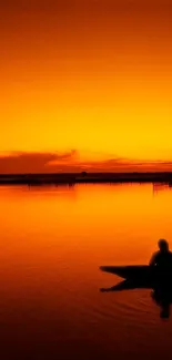 Silhouette of person kayaking during an orange sunset over calm waters.