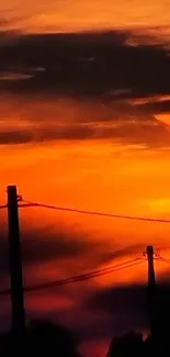 Vibrant dark orange sunset with silhouetted poles and wires.