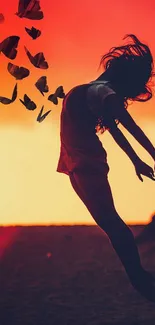 Silhouette of a girl leaping with butterflies against a sunset background.