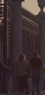 A group walking by ornate gates at sunset, creating a tranquil scene.