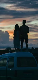 Couple on van watching sunset with scenic landscape.