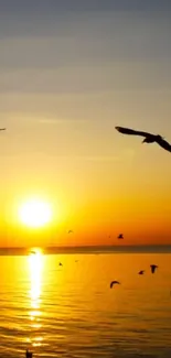 Sunset with birds flying over ocean waves.