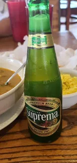 Suprema beer bottle on a dining table with food.