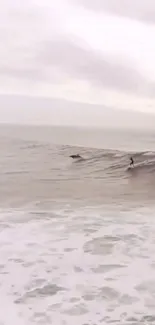 Surfer gliding on calm ocean waves under cloudy sky.