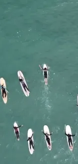 Aerial view of surfers on aqua green ocean waves.