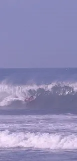 Surfer riding a large wave on a pale lavender ocean.