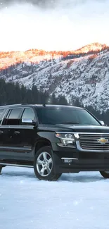 Sleek black SUV on snowy terrain with a mountain backdrop.