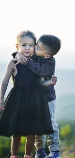 Two kids in a meadow at sunset.