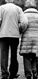 Black and white image of an elderly couple walking.