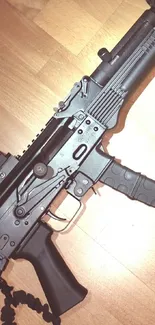 Mobile wallpaper of a tactical black rifle on a wooden floor.