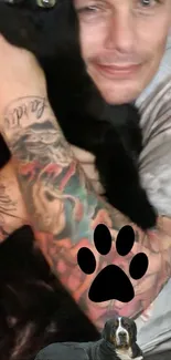 Tattooed arm holding a black cat with a dog at the bottom.