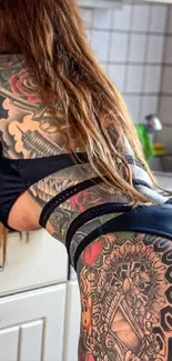 Woman with artistic tattoos in kitchen setting.