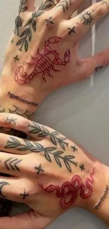 Hands with artistic tattoos featuring scorpion and snake ink designs.