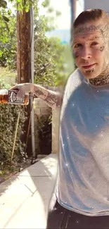 Tattooed man in sunlight holding bottle outdoors.