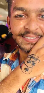 Smiling man with tattoo and colorful shirt.