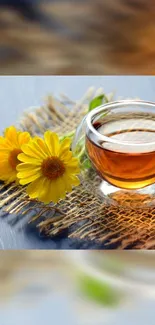 Glass cup of tea with yellow flowers on a rustic mat.