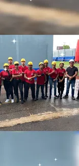 Group of workers in helmets and red shirts at construction site.