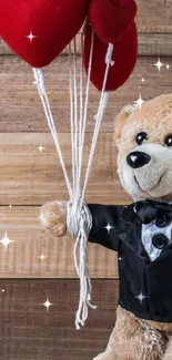 Teddy bear in tuxedo with heart balloons on wood.