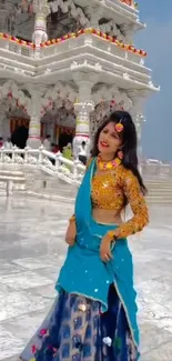 Woman in traditional attire at a temple with intricate architecture.