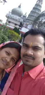 Couple in traditional attire with temple background.