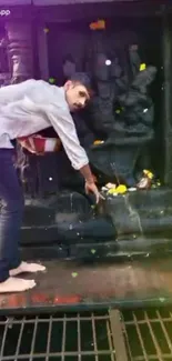 Devotee offering flowers at stone-carved temple shrine.