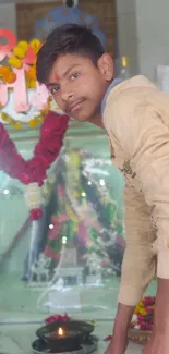 Young man standing in a temple with vibrant decorations.