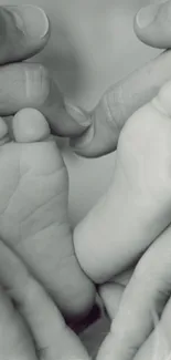 Gentle hands cradle baby's feet in a soft, gray-toned wallpaper.