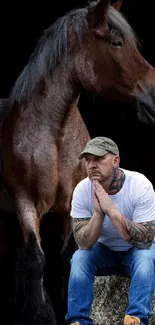 Man seated beside a majestic brown horse on a dark background.