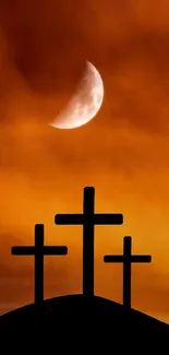 Silhouette of three crosses at sunset with moon in orange sky.