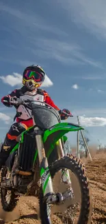 Dirt bike rider on a green motorcycle under blue skies.