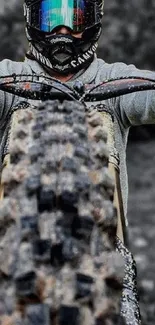 Biker performing stunt on dirt bike with rugged terrain in background.