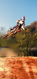 Motocross rider jumps over a dirt track in a vibrant forest scene.