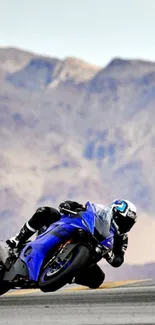 Blue motorcycle on mountain road with rider leaning into turn.