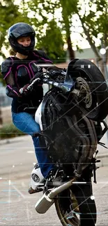 Motorcycle stunt rider performing a wheelie in an urban setting.