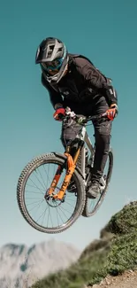 Mountain biker jumps on rugged terrain with a blue sky backdrop.