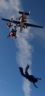 Skydivers jumping from a plane under a clear blue sky.