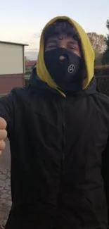 Person with thumb up, wearing a hood and mask.