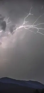 A vivid lightning strike illuminates a dark, stormy night sky over distant mountains.